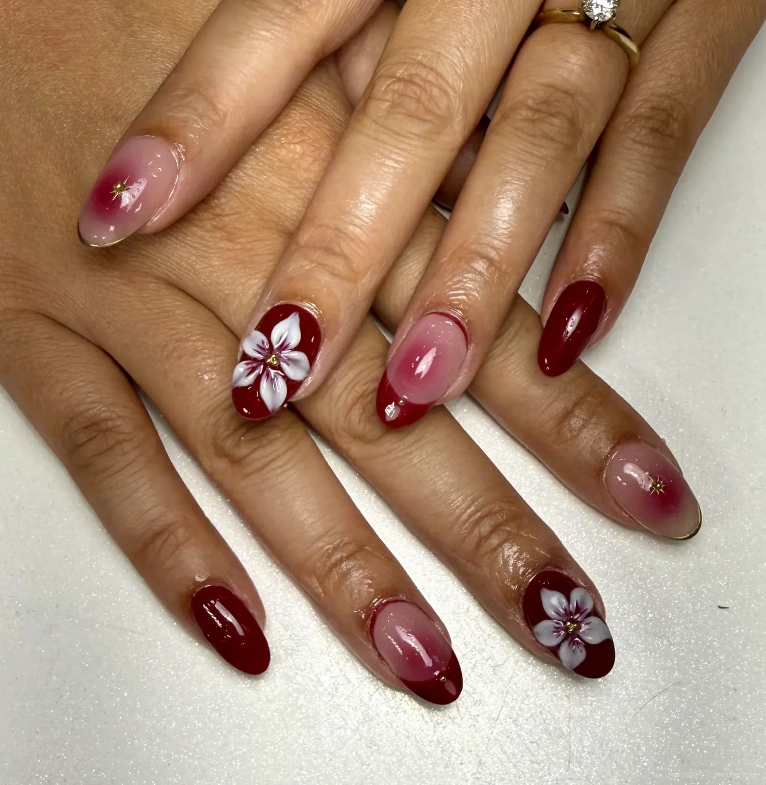 Glossy red and pink nails with white flower art